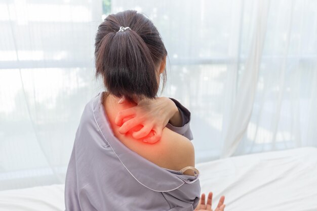 mujer con picazón en la parte de atrás del hombro y rascarse en la cama después de despertarseConcepto de atención médica