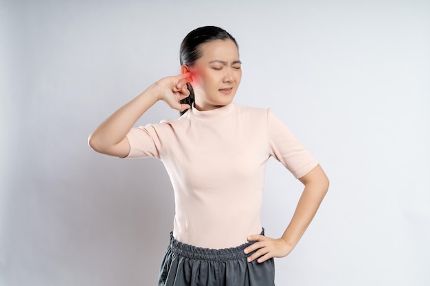 Mujer picazón poniendo un dedo en la oreja con punto rojo