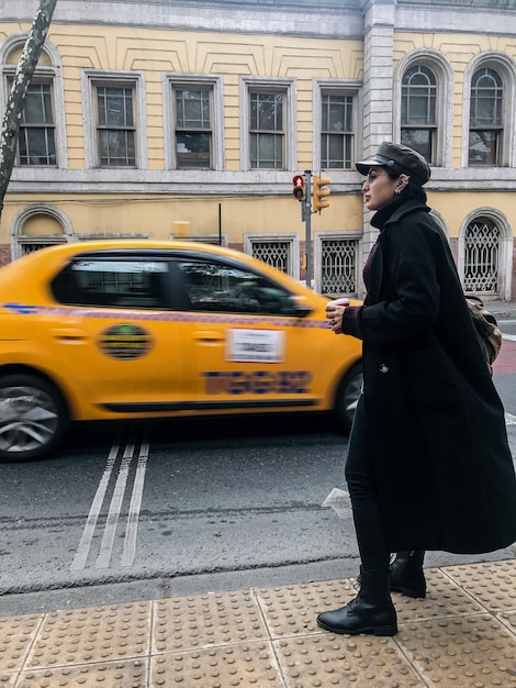 Foto mujer de pie en la acera de la ciudad