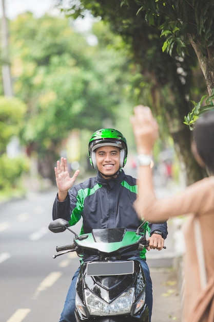 Mujer de pie en la acera ordenando moto taxi