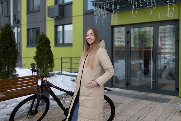 Mujer de pie al lado de la bicicleta frente al edificio