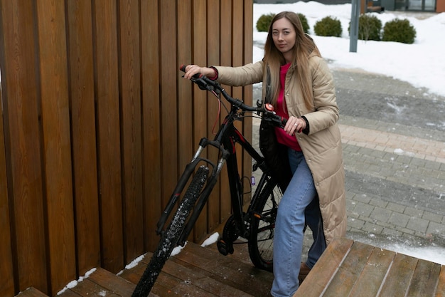 Mujer de pie al lado de la bicicleta en la nieve