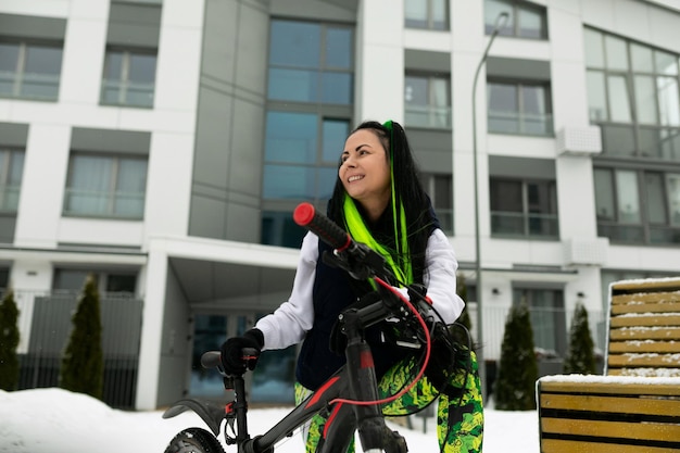 Foto mujer de pie al lado de la bicicleta en la nieve