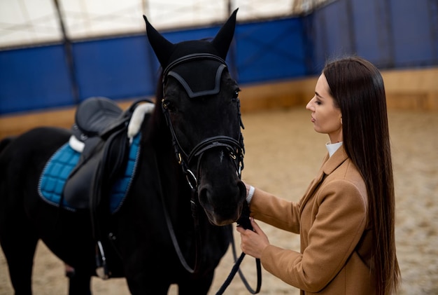 Una mujer de pie al lado de un caballo negro