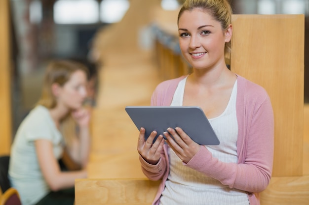 Mujer de pie en la biblioteca con tablet pc