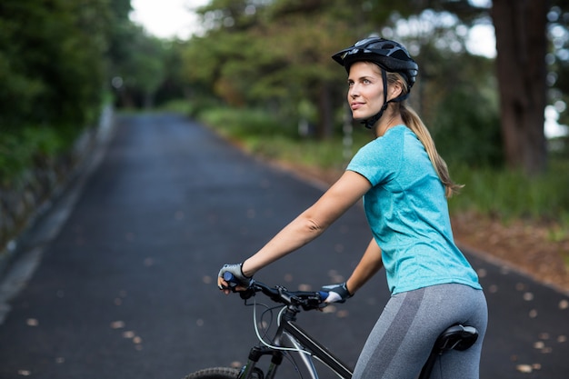 Mujer de pie con bicicleta de montaña en la carretera abierta