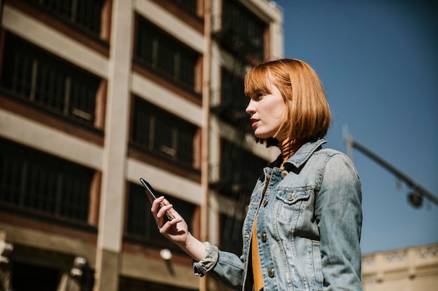 Mujer de pie en una calle con su teléfono