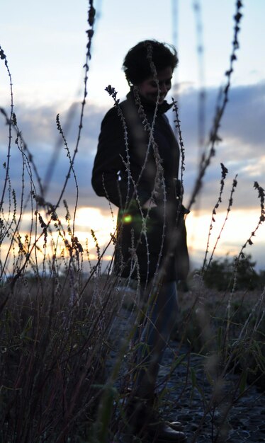 Foto mujer de pie en el campo contra el cielo durante la puesta de sol