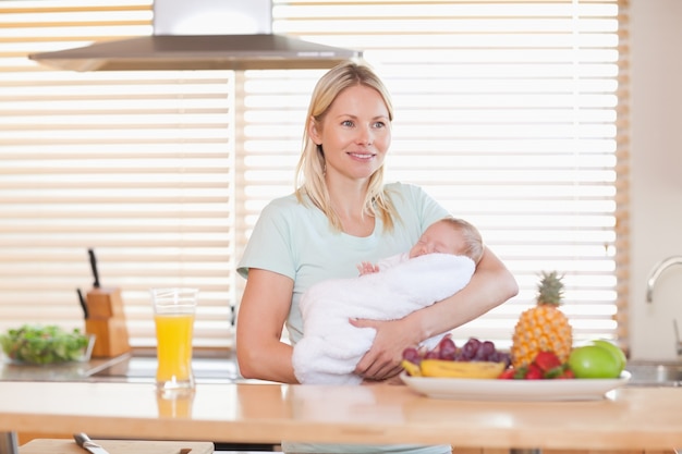 Mujer de pie en la cocina con su bebé