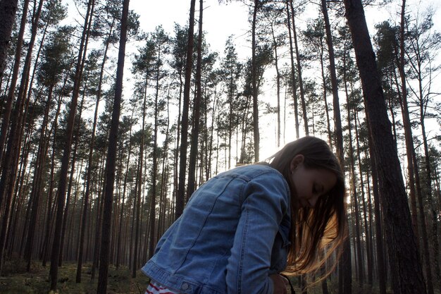 Foto mujer de pie contra los árboles en el bosque