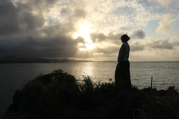 Foto mujer de pie contra el cielo durante la puesta de sol