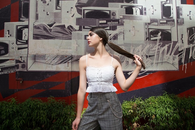 Foto mujer de pie contra una pared de graffiti