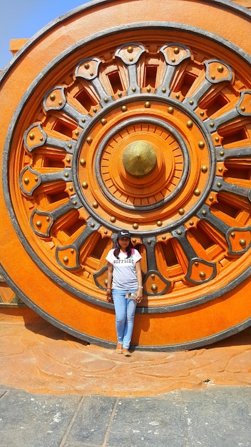 Foto mujer de pie contra la rueda del carro