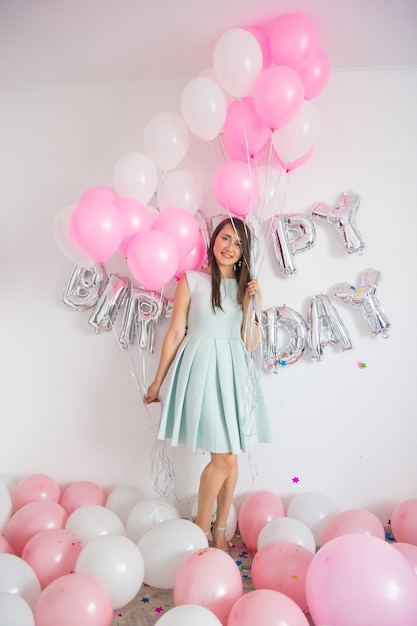 Mujer de pie en decoraciones con globos y confeti para fiesta de cumpleaños