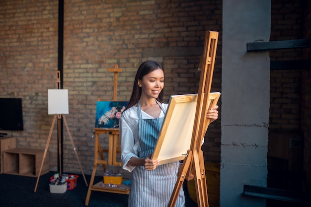 Mujer de pie delante del caballete mientras trabajaba en el estudio de arte