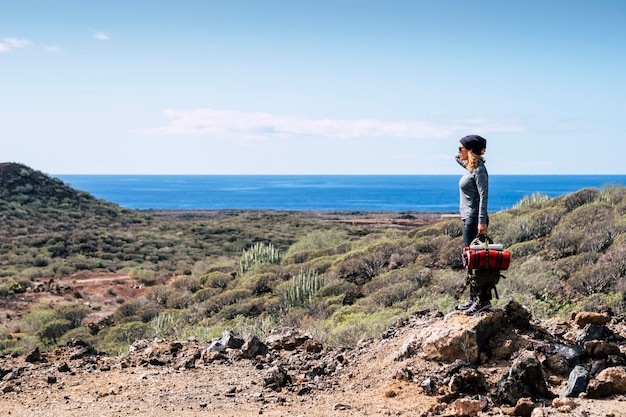 Una mujer de pie disfrutando y admirando el paisaje panorámico en una actividad de ocio al aire libre después de una caminata de senderismo Vista al mar y al mar con cielo azul en el horizonte Estilo de vida de viaje y aventura