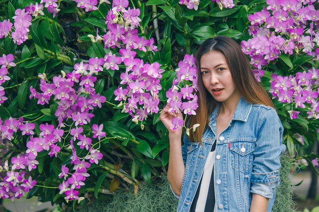 Una mujer de pie en una hermosa flor de orquídea rosa