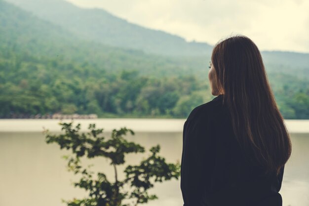 Mujer de pie junto al árbol contra la montaña