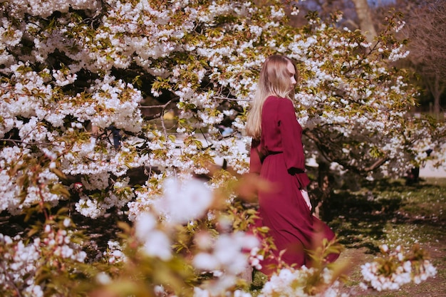 Foto mujer de pie junto al cerezo en flor