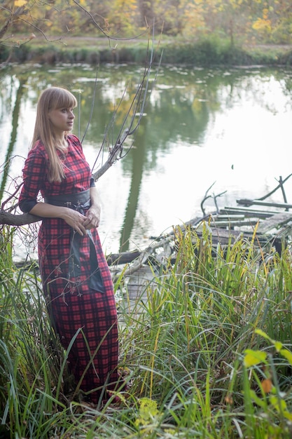 Mujer de pie junto al río con un vestido rojo a cuadros