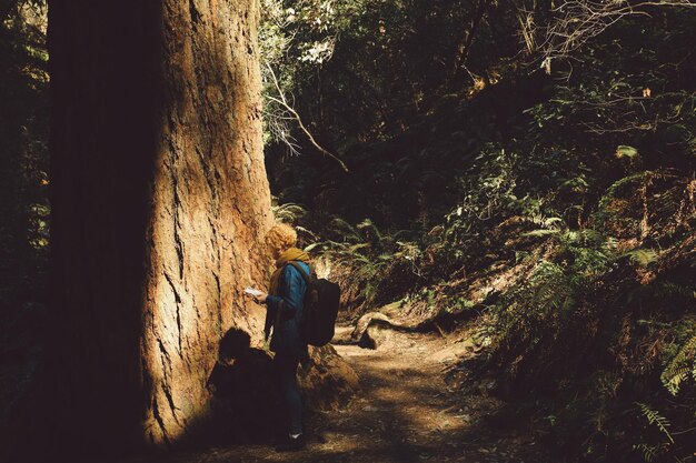 Mujer de pie junto a un árbol en el bosque