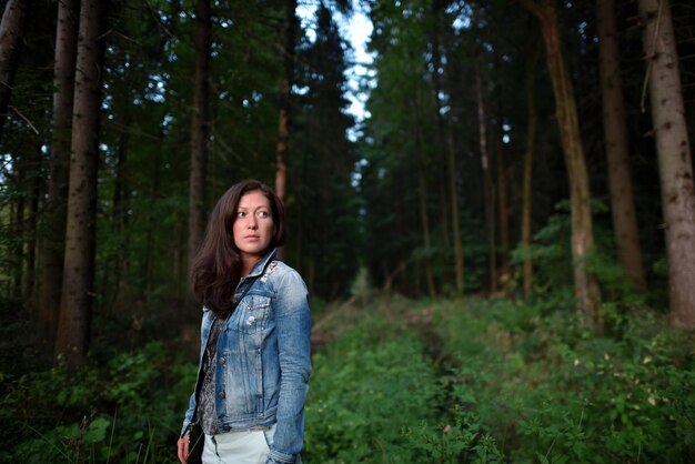 Mujer de pie junto a los árboles en el bosque