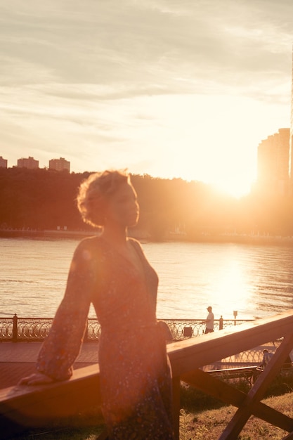 Foto mujer de pie junto a la barandilla contra el mar durante la puesta de sol