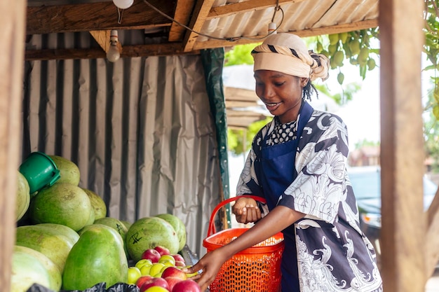 Mujer de pie junto a una pila de frutas