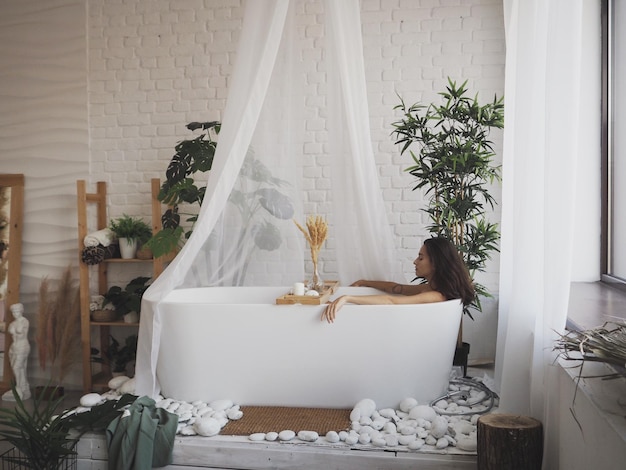 Foto mujer de pie junto a una planta en maceta en casa