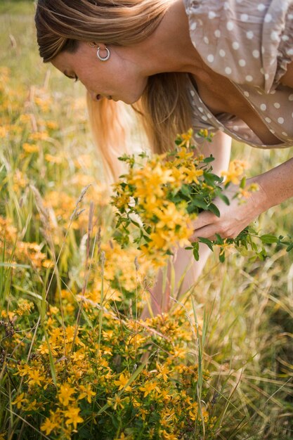 Mujer de pie junto a las plantas en flor en el campo