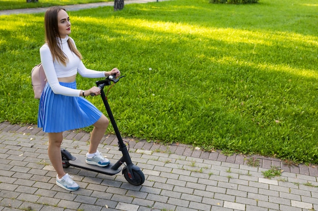 Mujer de pie junto a scooter helectric en el parque