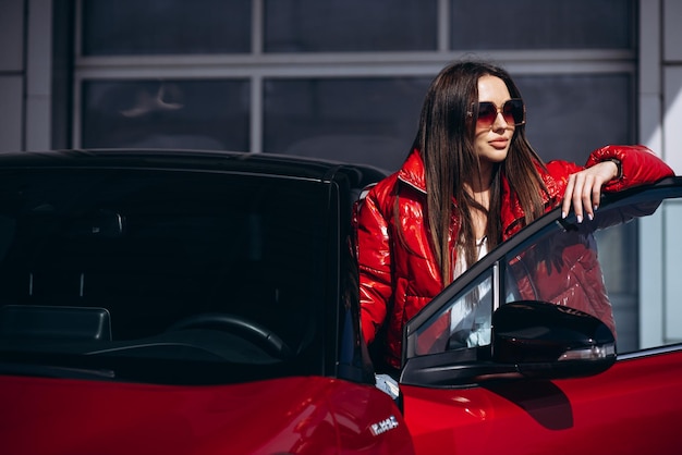 Mujer de pie junto a su nuevo coche rojo