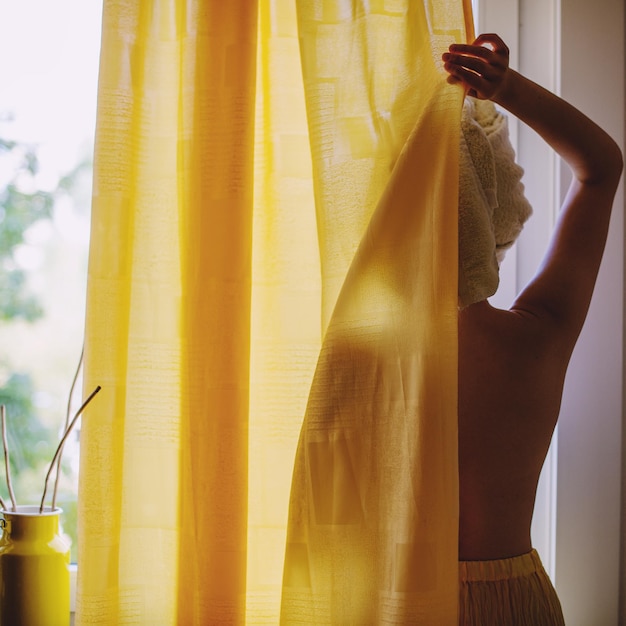 Mujer de pie junto a la ventana en casa