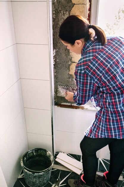 Foto mujer de pie junto a la ventana en casa