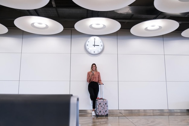 Mujer de pie leyendo smartphone en el aeropuerto