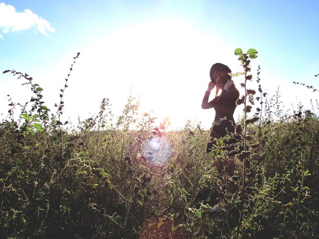 Foto mujer de pie en medio de plantas contra el cielo