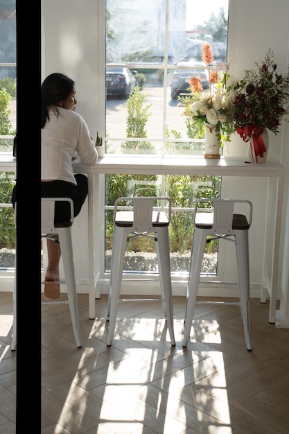 Foto mujer de pie en la mesa junto a la ventana