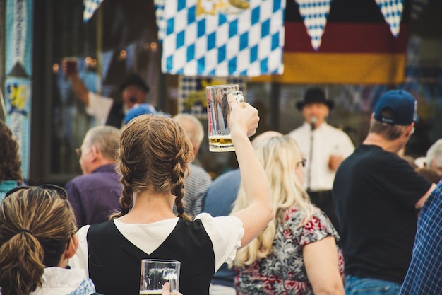 Mujer de pie en una multitud sosteniendo una foto de vaso de cerveza