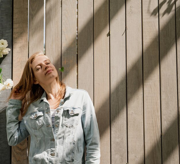 Mujer de pie en una pared de madera y luz solar natural