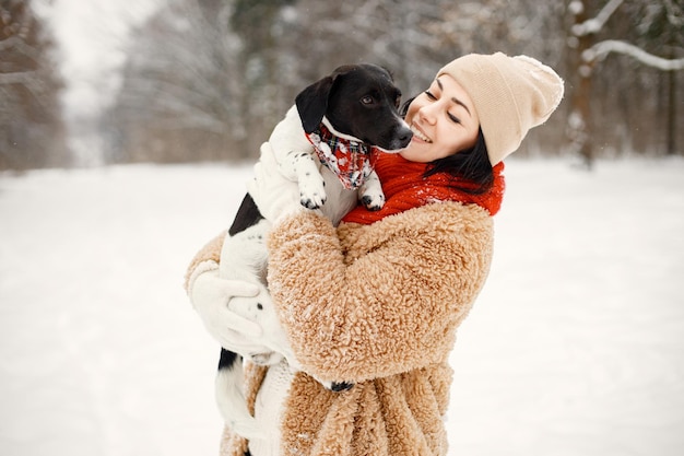 Mujer de pie en el parque de invierno y sosteniendo un perro negro