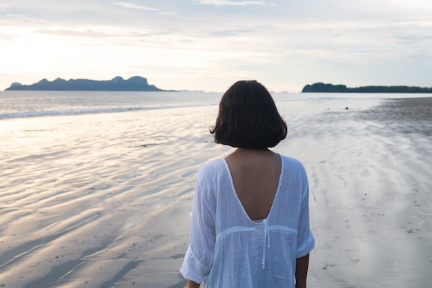 mujer de pie en la playa de arena