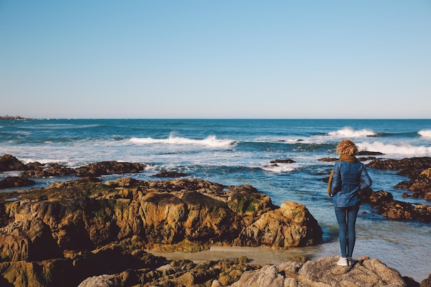 Foto mujer de pie en la playa contra el cielo azul claro