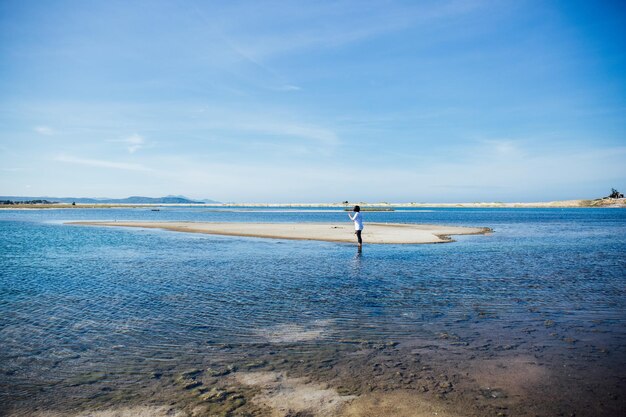 Mujer de pie en la playa contra el cielo