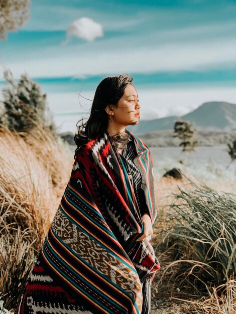 Foto mujer de pie en la playa contra el cielo