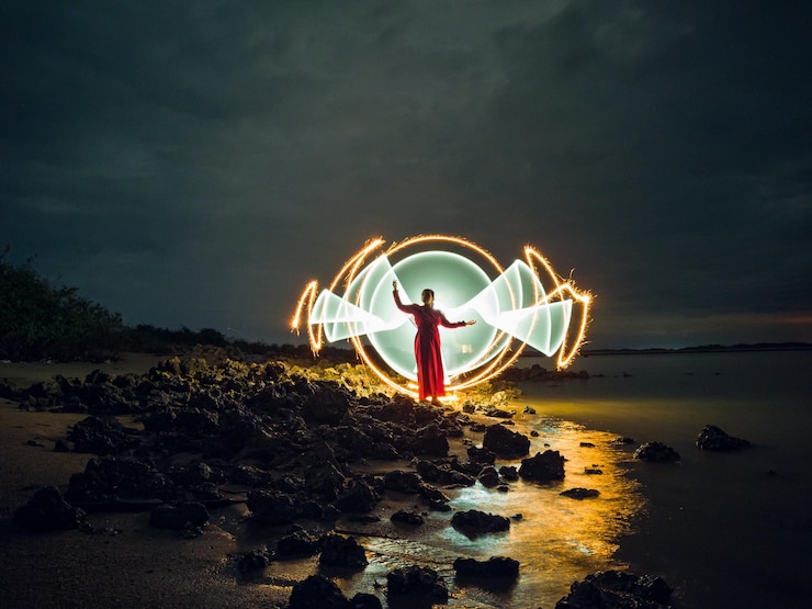 Foto mujer de pie en la playa iluminada contra el cielo por la noche