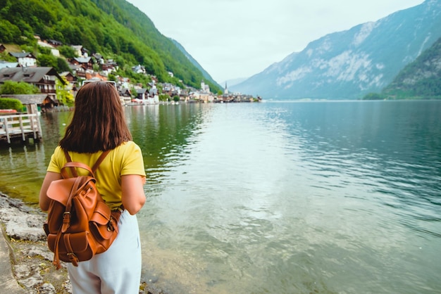 Mujer de pie en la playa mirando la ciudad de hallstatt en los alpinos austriacos