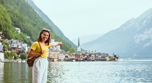 Foto mujer de pie en la playa mirando el espacio de copia de la ciudad de hallstatt apuntando a la ciudad