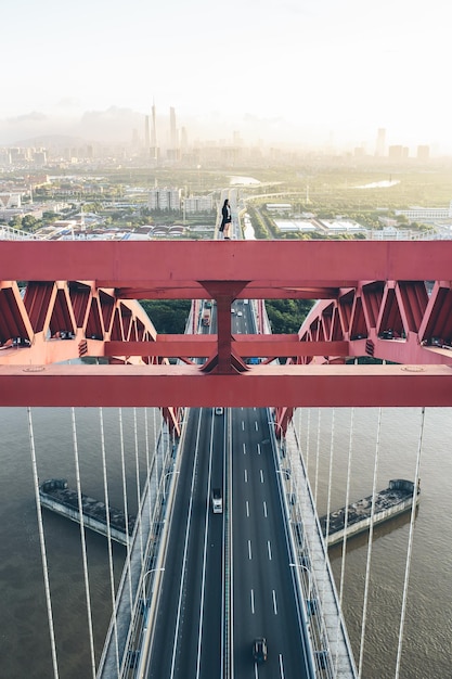 Mujer de pie en un puente de cables sobre un río en la ciudad