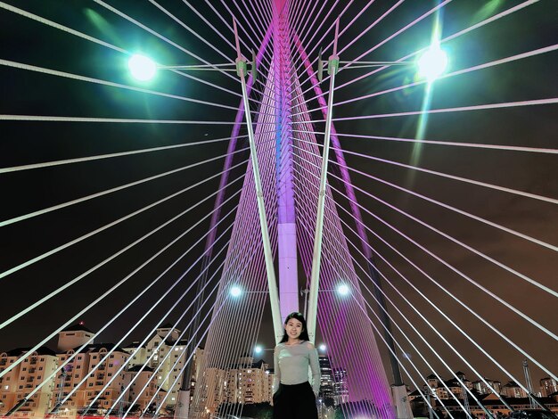 Foto mujer de pie en un puente iluminado por la noche