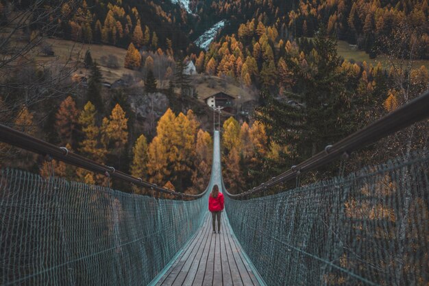 Mujer de pie en un puente peatonal en el bosque